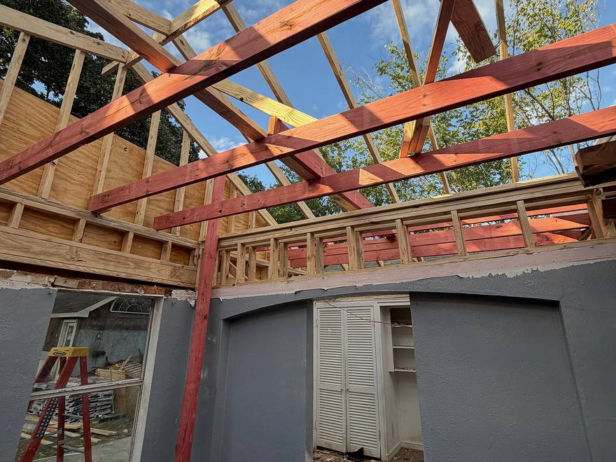 Room opened up to new ceiling framing, with a temporary shoring post, during a ceiling raise in Dallas